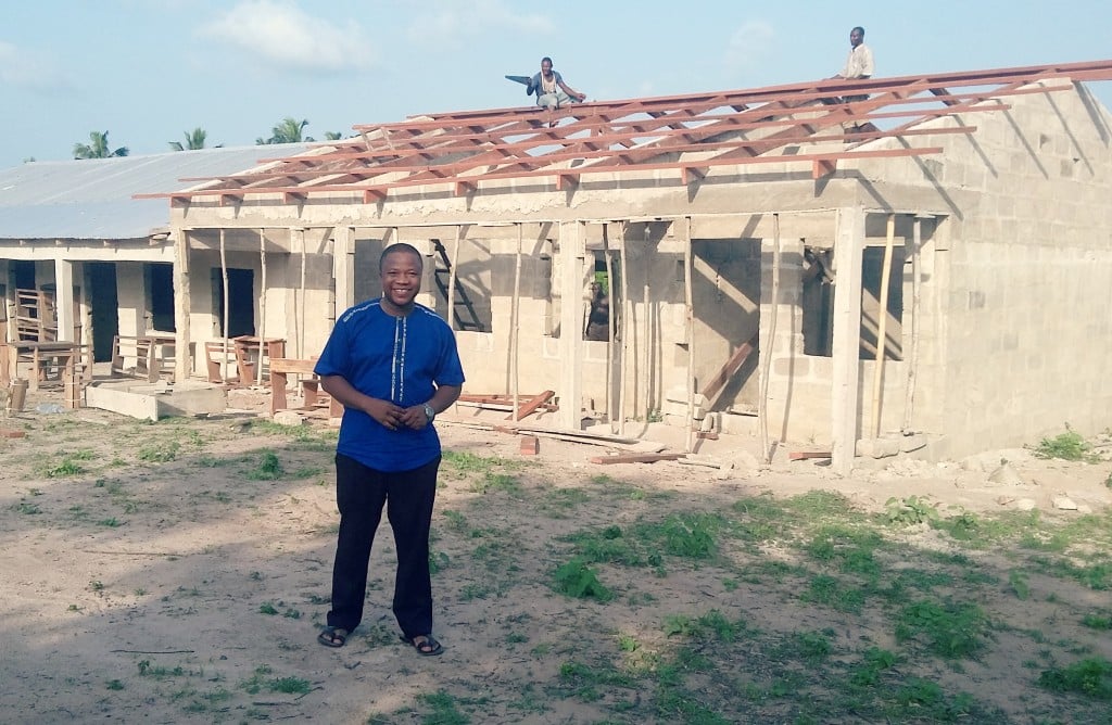 Benson Adjei stands in front of the Adansimaim Basic School during its construction.